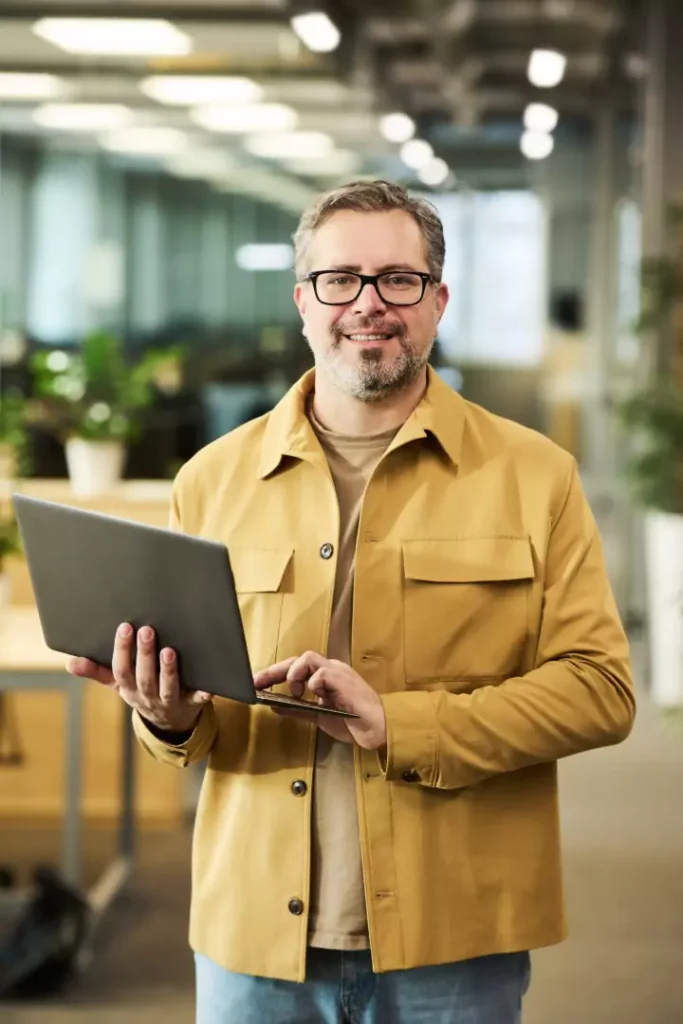 Smiling account manager holding a laptop in the office